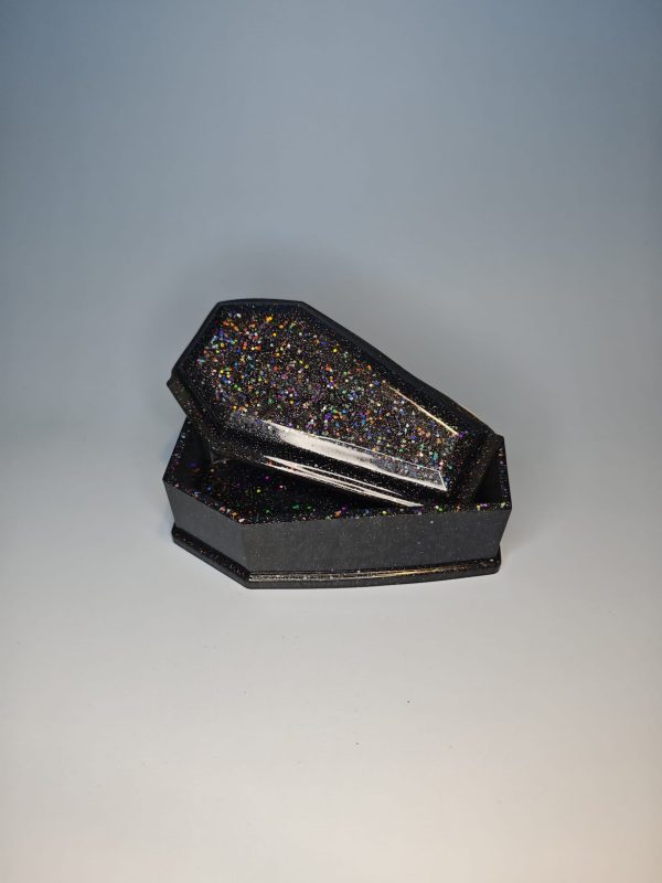 A coffin shaped black box with glittery surface with a lid