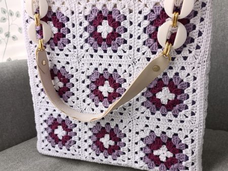 Handmade boho crochet bag in white, purple, and lilac granny squares with magnetic closure