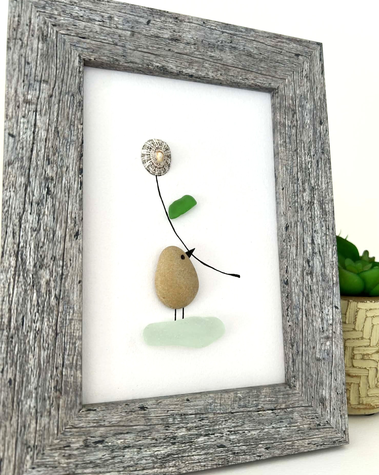 Minimalist Coastal Art – Pebble & Seaglass Scene with a Cute Bird Holding a Flower