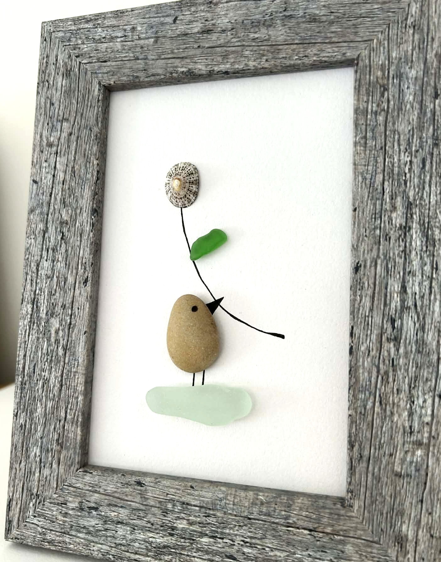 Minimalist Coastal Art – Pebble & Seaglass Scene with a Cute Bird Holding a Flower